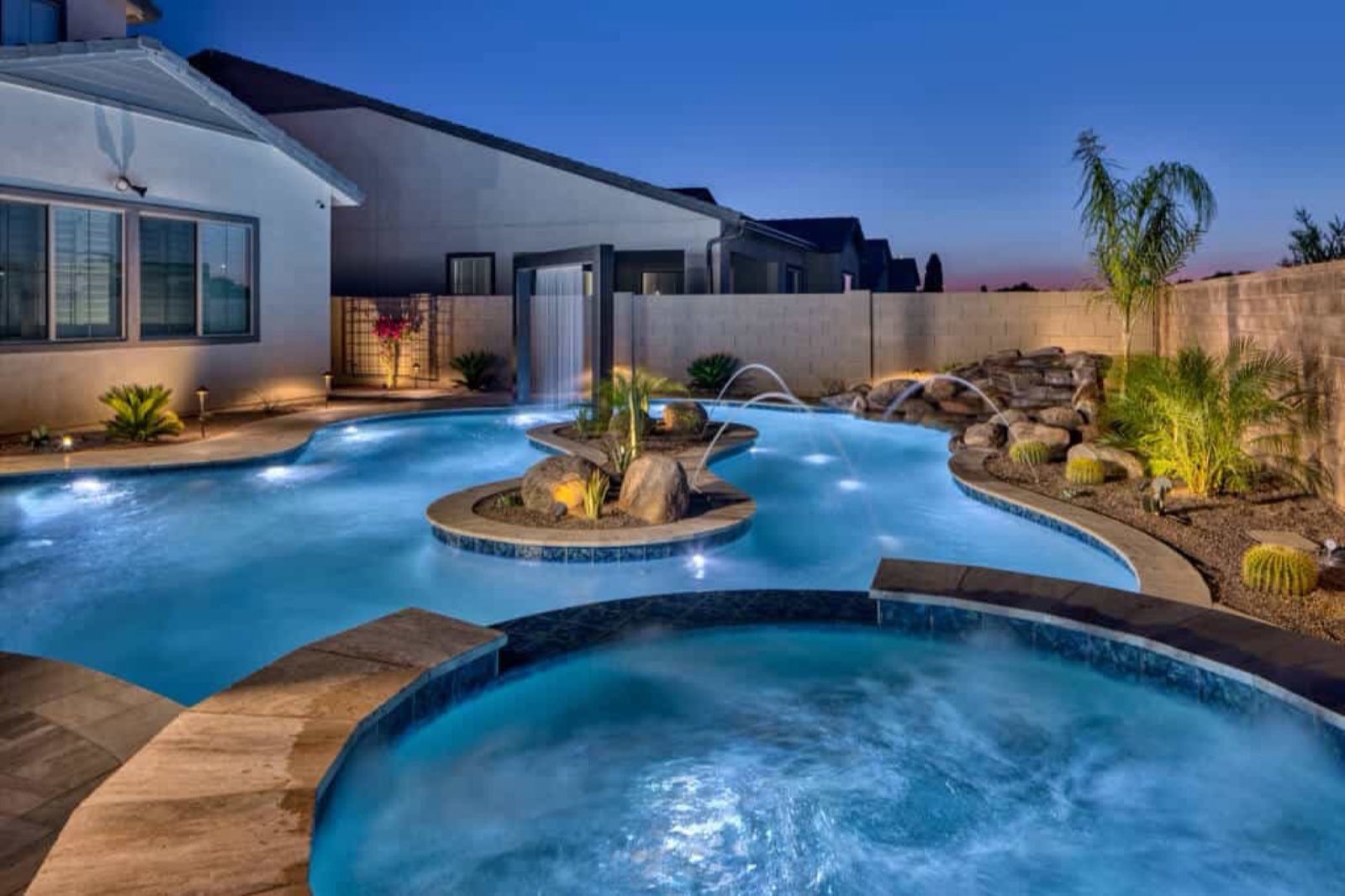 Backyard pool with landscape lighting and lit water features at dusk