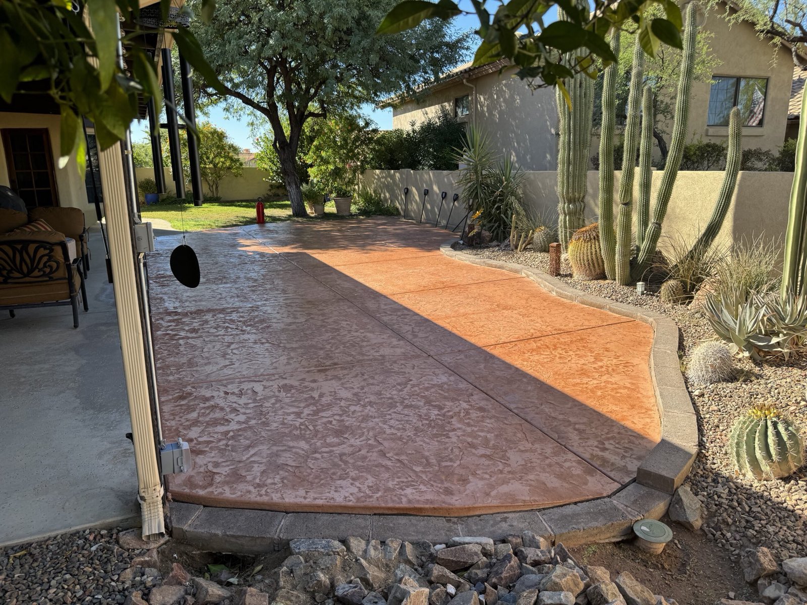 Stained decorative concrete patio with a paver border and desert landscaping in a Tucson backyard
